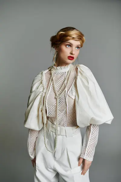 stock image A young woman with red lipstick and a pearl necklace poses in a white lace blouse and pants.