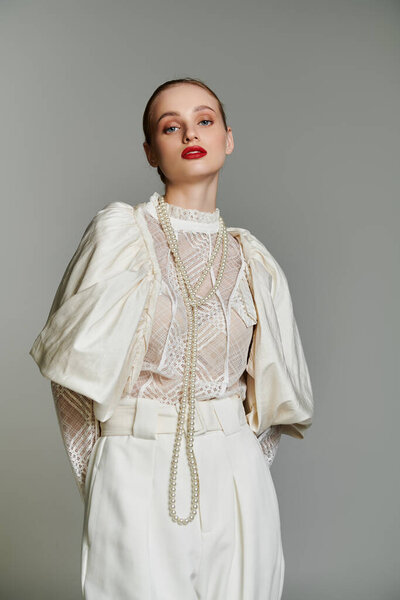Young woman in white lace outfit with pearl necklace in studio.
