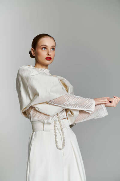 A young woman in a white outfit poses with a confident gaze.