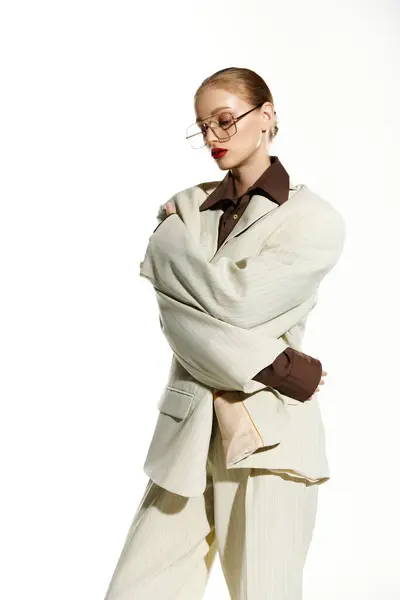 stock image A woman in a white suit stands with her arms crossed, looking down.