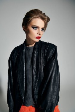 Siyah makyajlı ve deri ceketli bir kadın stüdyoda poz veriyor..