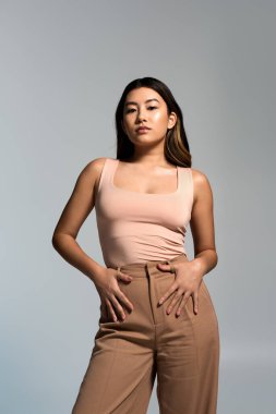 Genç bir kadın kendine güvenerek ayakta duruyor, elleri kalçasında dinleniyor, kendine güvenini yayıyor..