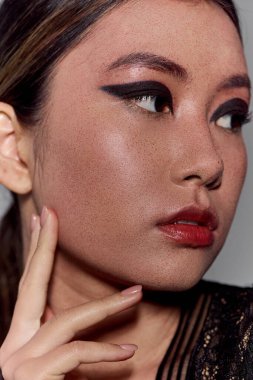 Kusursuz derisi, siyah göz kalemi, kırmızı ruju olan Asyalı kadının yakın çekimi..
