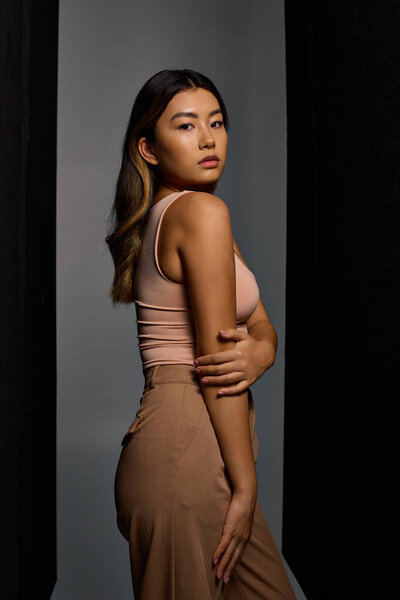 A woman stands confidently in a studio, her stylish attire highlighting her grace.