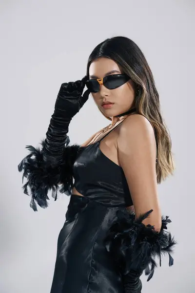 stock image A woman in a black dress and feather gloves poses with a confident smirk.