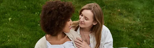 stock image Two women share a tender moment outdoors, their eyes locked in affection.