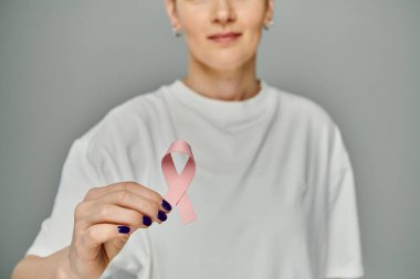 Bir kadın elinde pembe bir kurdele tutuyor. Meme kanseri farkındalığının sembolü..