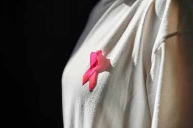Göğüs kanseri farkındalığını sembolize eden, bir kadının gömleğine tutturulmuş pembe bir kurdele..