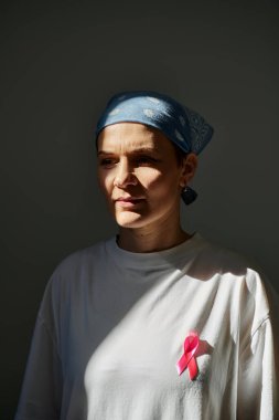 Bir kadın göğüs kanseri farkındalığını simgeleyen pembe bir kurdele ve mavi bir bandana takıyor..