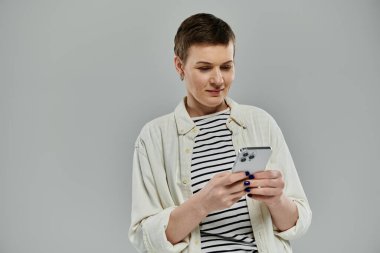 Kısa saçlı bir kadın gündelik ortamında akıllı telefon kullanır..