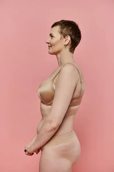 stock image A woman with short hair stands in profile, wearing a bra