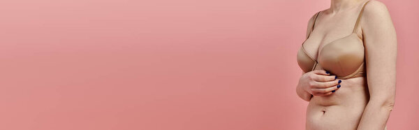 A woman in a bra touches her chest, signifying breast cancer awareness.