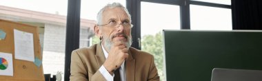 A mature LGBTQ teacher with a beard contemplates his next lesson while teaching online from his laptop. clipart