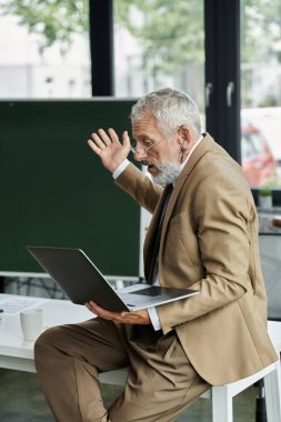 A bearded professor, clad in a suit, passionately teaches online through his laptop, captivating his students. clipart