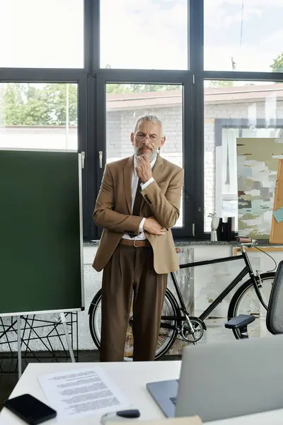 stock image A mature gay teacher with a beard ponders a question while teaching online in a modern office setting.