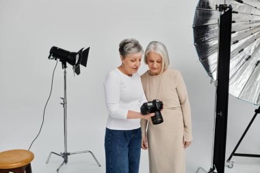 Yetişkin bir lezbiyen çift profesyonel bir fotoğraf çekiminden zevk alıyor, çekilen görüntüleri inceliyor..