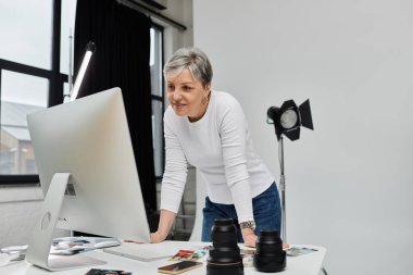 Bir kadın fotoğraf stüdyosundaki bilgisayar ekranında fotoğrafları inceliyor..