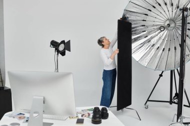 Bir fotoğrafçı bir fotoğraf stüdyosundaki ışıklandırma panelini ayarlar..