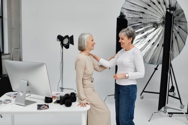 Bir fotoğrafçı fotoğraf stüdyosunda modelinin pozunu ayarlar. Hem güler hem de güler..