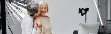 A mature lesbian couple shares a tender moment during a photoshoot in a studio. clipart