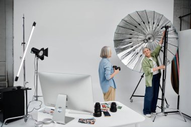 Yetişkin bir lezbiyen çift stüdyoda fotoğraf çekmekten hoşlanır. Biri poz verirken diğeri fotoğraf çeker..