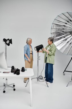 İki olgun lezbiyen kadın, biri model, diğeri fotoğrafçı olarak stüdyoda fotoğraf çekilirken..