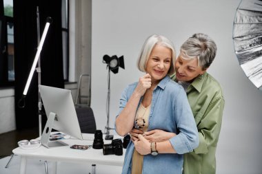 Lezbiyen bir çift stüdyo fotoğrafı çekilirken şefkatli bir kucaklaşmayı paylaşıyor.