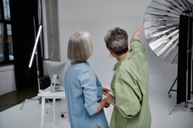 Fotoğraf stüdyosunda bir lezbiyen çift, biri fotoğrafçı, diğeri de model olarak çalışıyor, ışıklandırma seçeneklerini tartışıyorlar..