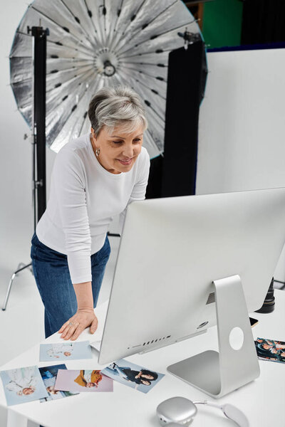 A photographer leans over a computer, reviewing images from a recent photoshoot.