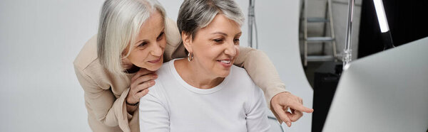 Two women, partners, review photographs together during a studio photo shoot.