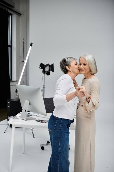 A photographer kisses her model during a photo shoot in a studio.