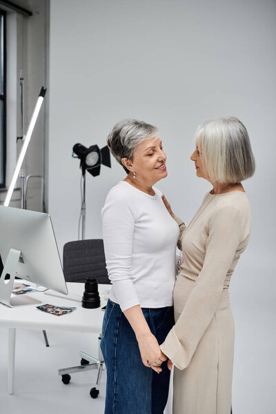 Two women, a photographer and her model, stand close and look into each other eyes during a photo shoot.