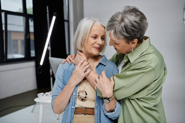 A mature lesbian couple embraces in a photo studio