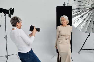 Olgun bir lezbiyen çift stüdyoda fotoğraf çekmekten hoşlanır. Bir kadın diğerinin fotoğrafını çeker..