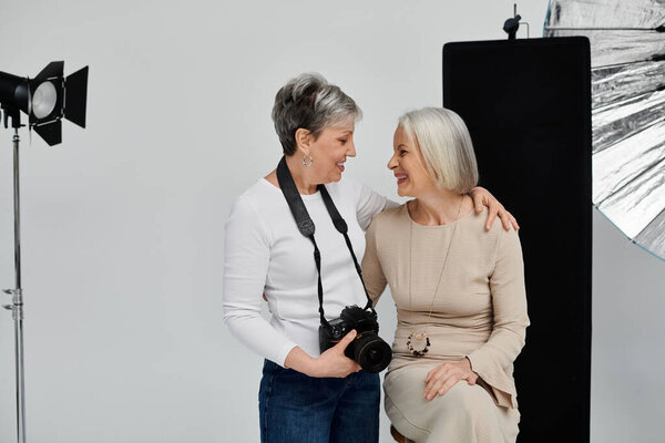 A photographer captures a tender moment between two women in a studio, their laughter and love radiating through the soft lighting.