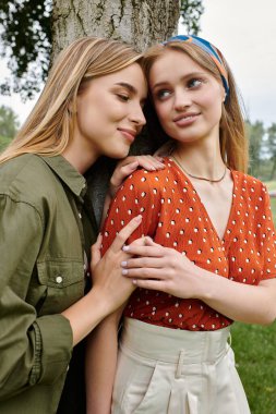 İki genç kadın yemyeşil bir parkta hassas bir anı paylaşıyor..