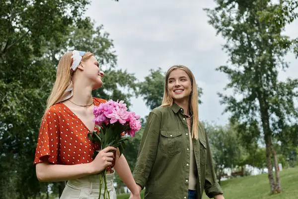 stock image A young lesbian couple walks hand-in-hand through a lush park, enjoying the sunshine and each other company.