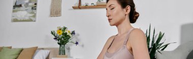 Ekin giysili genç bir Asyalı kadın modern bir dairede yoga ve meditasyon yapıyor..