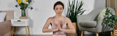 Ekinlerin içinde genç bir kadın gözleri kapalı meditasyon yapıyor, modern bir dairede oturuyor..