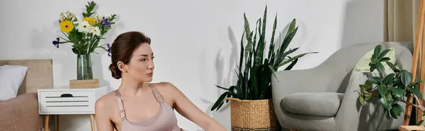 stock image A beautiful Asian woman in a crop top meditates in a modern apartment filled with plants and natural light.