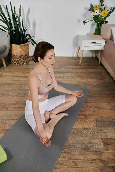 stock image A woman in a crop top practices yoga and meditation on a mat in a contemporary apartment.