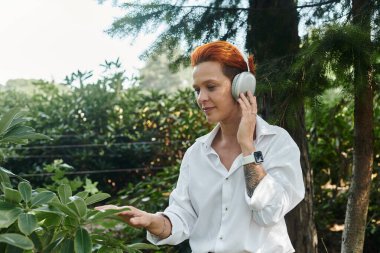 Bir öğretmen kampüste dışarıda eğlenirken kulaklıkla müzik dinler..