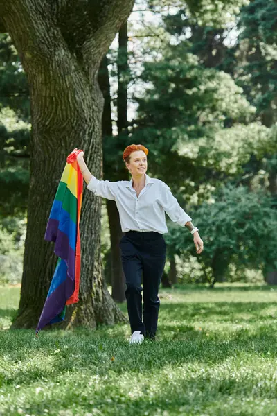 Stock image A teacher walks through campus grounds, holding a rainbow flag.