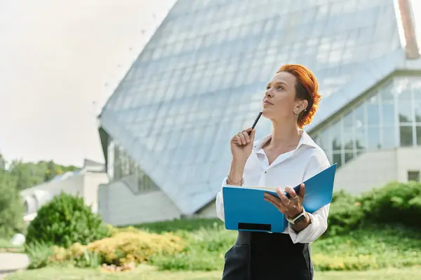 stock image Redhead woman outside campus, notebook and pen, lost in thought