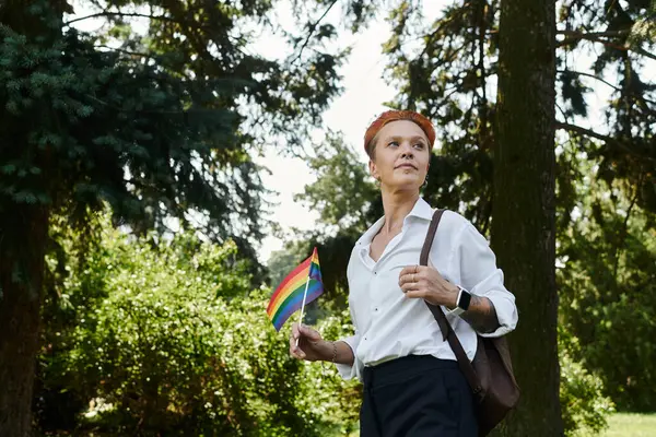 stock image A teacher walks through a campus, holding a rainbow flag.