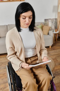 Tekerlekli sandalyede oturan bir kadın tabletine konsantre oluyor..