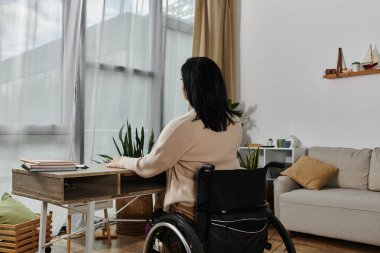 Tekerlekli sandalyede oturan bir kadın pencereden dışarı bakıyor..