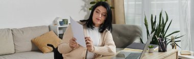 Tekerlekli sandalyedeki bir kadın masaya oturur ve gazete okur..