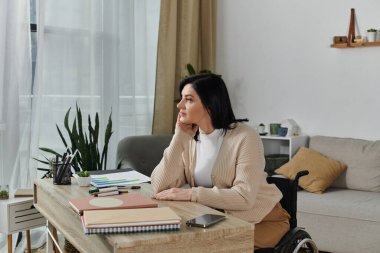 Tekerlekli sandalyedeki kadın pencereden bakar, çenesi dinlenir.