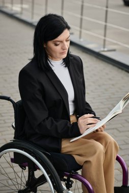 Tekerlekli sandalyedeki bir kadın dışarıda oturmuş kitap okuyor..